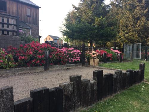 a garden with pink flowers behind a wooden fence at L'orée du bois in Roy