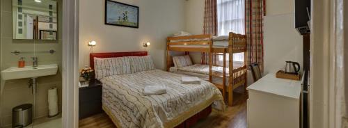 ロンドンにあるバリー ハウスの小さなベッドとシンクが備わる小さな客室です。