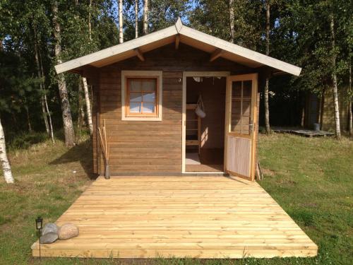 a small wooden cabin with a door and a porch at Suurkivi Nature Escape in Häädemeeste