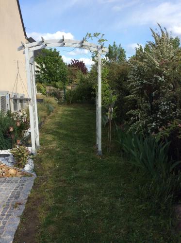 a white pergola in the yard of a house at Tercier de vigne in Chécy