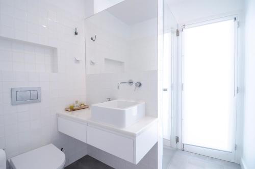 Baño blanco con lavabo y aseo en Évora Art&Accommodation, en Évora