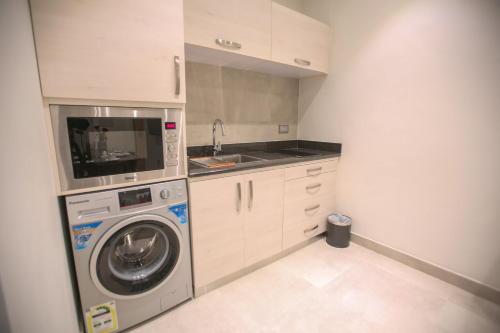 a small kitchen with a washing machine and a sink at Tanuma Aram Hospitality - Hotel Apartments in Tanomah
