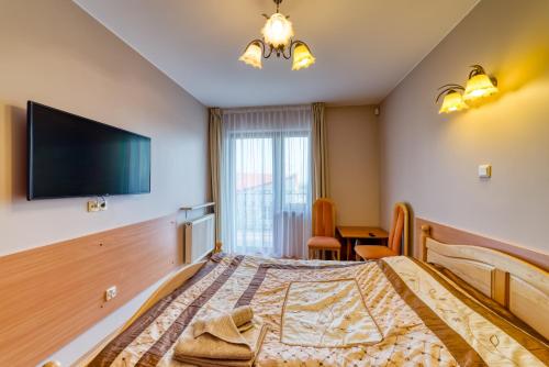 a bedroom with a bed and a flat screen tv at Willa Joker in Krynica Morska