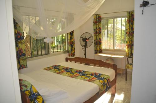 sypialnia z łóżkiem w pokoju z oknami w obiekcie Vokundahouse w mieście Kololi