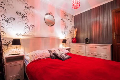 a bedroom with a red bed with a red blanket at Apartament Słoneczna in Zakopane