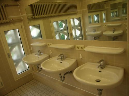La salle de bains est pourvue de 3 lavabos et d'un miroir. dans l'établissement Jugendgästehaus St.-Michaels-Heim, à Berlin
