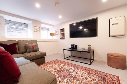 a living room with a couch and a tv on the wall at The Roseate Edinburgh - Small Luxury Hotels of the World in Edinburgh