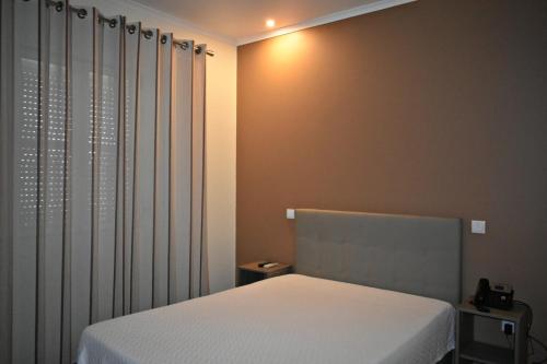 a bedroom with a white bed and a curtain at Horta D'Alva in Castelo Branco