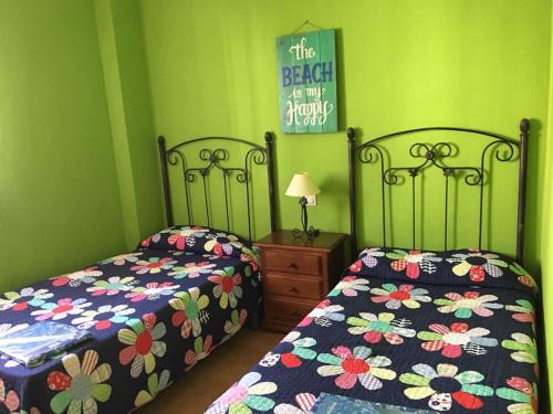 two beds in a bedroom with green walls at BONITO APARTAMENTO EN ZAHARA DE LOS ATUNES in Zahara de los Atunes