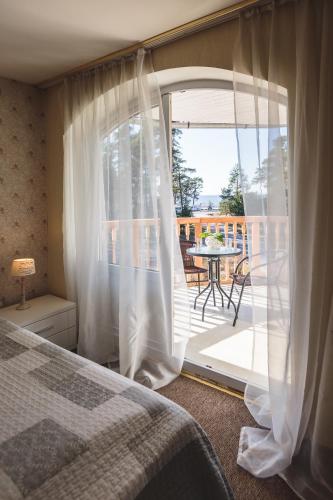 a bedroom with a bed and a balcony with a table at Karle Hotel in Vitrupe