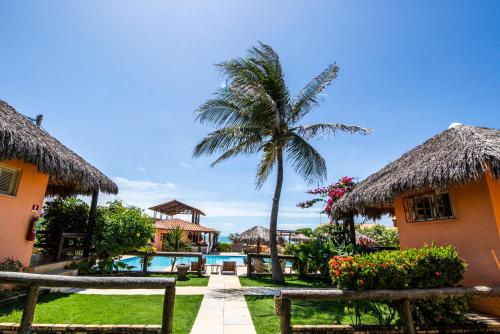 een resort met een palmboom en een zwembad bij Pousada Tranquilandia Village in Canoa Quebrada