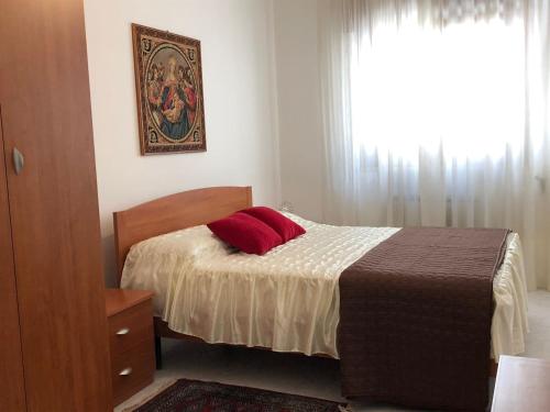 ein Schlafzimmer mit einem Bett mit einem roten Kissen darauf in der Unterkunft Dimora del '500 -City Apartment San Vito in San Vito dei Normanni