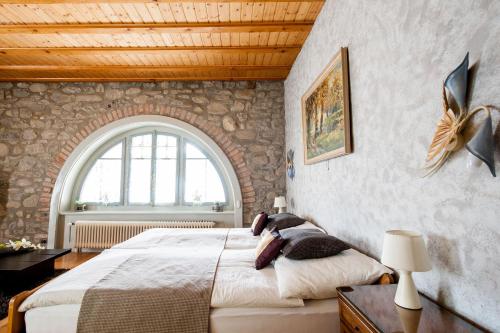 - une chambre avec un grand lit et un mur en pierre dans l'établissement Hotel Acacia, à Marly-le-Grand