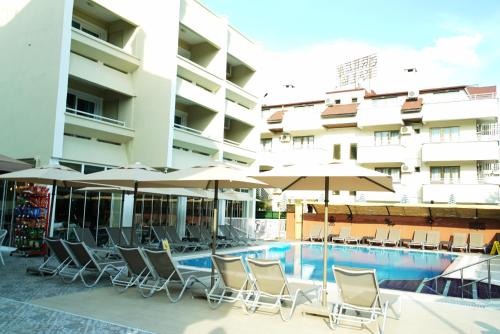 a hotel with chairs and umbrellas next to a swimming pool at Blue Palace Apart Hotel in Marmaris