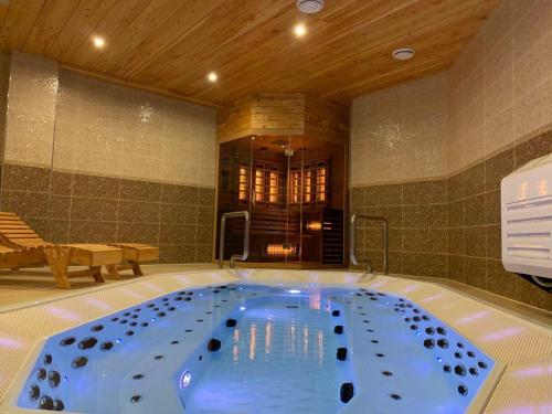 a jacuzzi tub in a room with a table and bench at Baron SPA Hotel - Museum Yaremche in Yaremche
