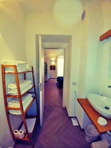 a bathroom with a sink and a shelf with towels at Le Nuvole di Ortigia in Syracuse