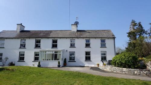 a large white house with a lawn in front of it at Gortamullen House, Kenmare in Kenmare