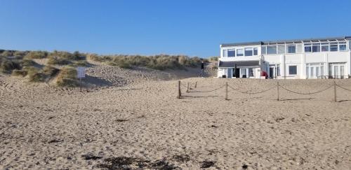 a house on the beach with a fence in the sand at Seagull's Crest in Camber