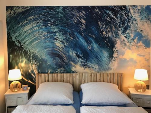 エッカーンフェルデにあるSEASIDE APARTMENTS - BEACHHOUSE BLUEの壁に絵画が飾られたベッドルーム1室(ベッド2台付)