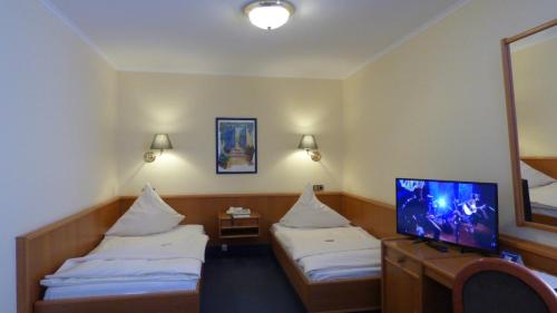 a hotel room with two beds and a flat screen tv at Central Hotel in Worms