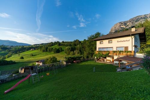 a large yard with a playground in front of a building at Trafisolerhof in Vols am Schlern