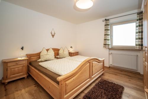 a bedroom with a wooden bed and a window at Trafisolerhof in Vols am Schlern