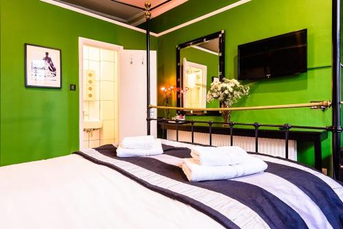 a bedroom with green walls and a bed with two pillows at Paskins Town House in Brighton & Hove
