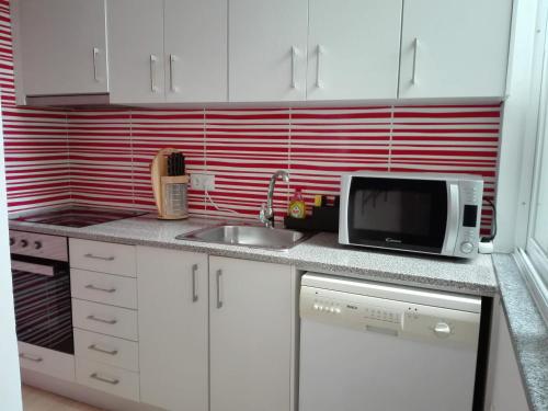 a kitchen counter with a microwave and a sink at Guesthouse Alentejo in Évora