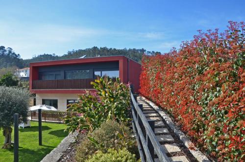 a red house with a hedge of flowers at Casa de Campo Sossego da Lata in Fafe