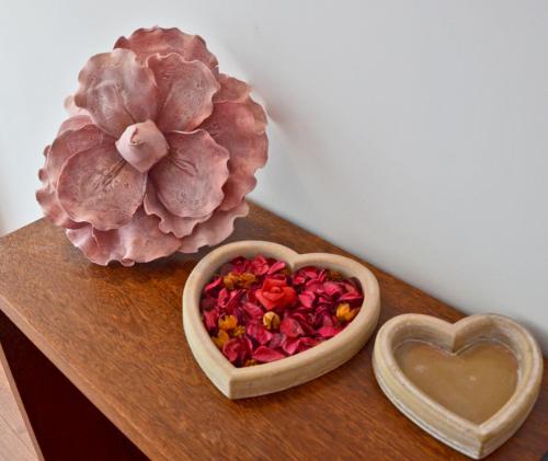 a wooden table with a bowl of flowers and a heart at Casa de Campo Sossego da Lata in Fafe