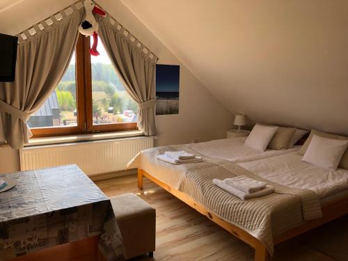 - une chambre avec un lit et une grande fenêtre dans l'établissement Willa Biały Dom, à Białogóra