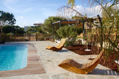 - une piscine avec 2 chaises longues à côté dans l'établissement Résidence U Rapalinu, à Molini