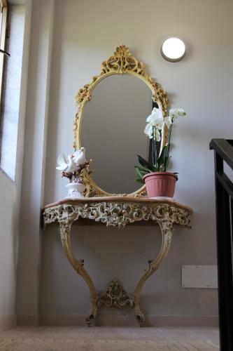 a console table with a mirror and flowers on it at IL FEUDO in Sellia Marina