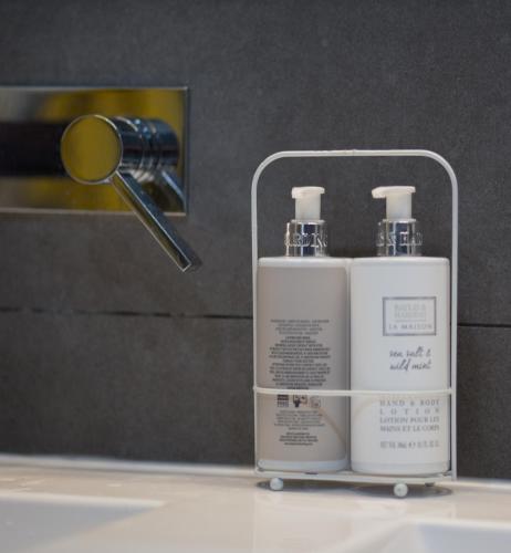 two bottles ofodorizers on a bathroom counter in front of a mirror at Spéciale Halloween - Idéal Familles & Groupes - 15min Parc Spirou - Nocturnes les 25, 30, 31 octobre et le 1er novembre - 10min Avignon - 5min Gare - Grand jardin clos - Parking gratuit - Au calme - Maison haut de gamme in Sorgues