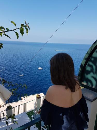 a woman standing on a balcony looking at the ocean at Hotel Villa Maria Pia in Praiano