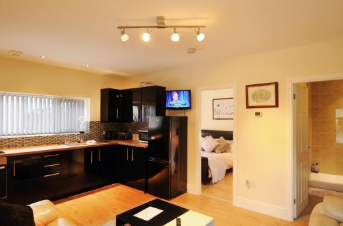 a kitchen with a black refrigerator and a bedroom at Orchid House in Southport