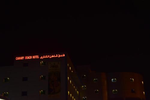 a building with a sign on top of it at night at Canary Beach Hotel in Yanbu