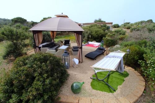 a garden with a gazebo and a couch and chairs at Villa Magdala in La Maddalena