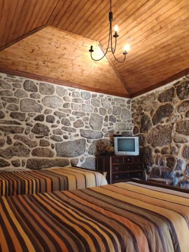 a bedroom with two beds and a stone wall at Casa Padre Alexandre in Covide