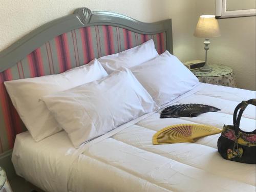 a white bed with white pillows and a purse on it at Fercamar Costacabana in Almería