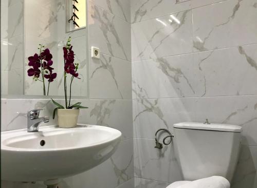 a white bathroom with a sink and a toilet at Joy Hotel in Sarandë