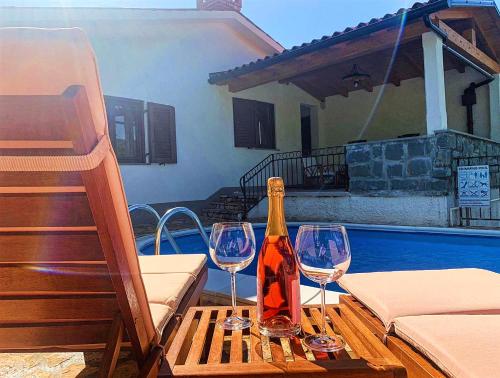 a bottle of wine and two wine glasses on a table at Holiday Home Deni in Roč