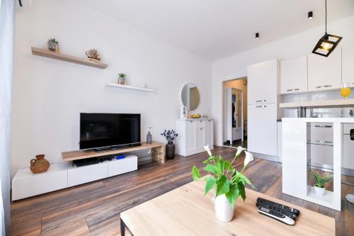 ein weißes Wohnzimmer mit einem TV und einem Tisch in der Unterkunft Serenity Apartment in Zadar