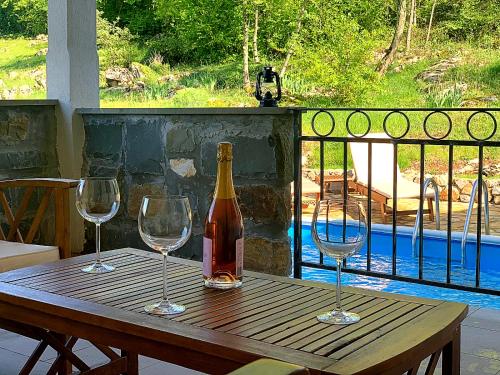 a bottle of wine and three wine glasses on a wooden table at Holiday Home Deni in Roč