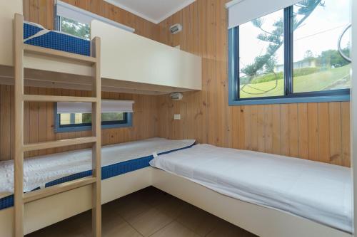 Tuross Beach Cabins & Campsites في توروس هيدز: سريرين بطابقين في غرفة مع نافذة