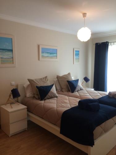 ein Schlafzimmer mit einem großen Bett und blauen Kissen in der Unterkunft Gomeira Top Floor in Cabanas de Tavira