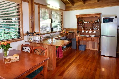 a kitchen with wooden floors and a stainless steel refrigerator at Sharlynn by the River in Malanda