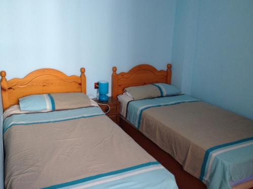 2 camas en una habitación pequeña con paredes azules en Casa La Guitarra, en Nerja