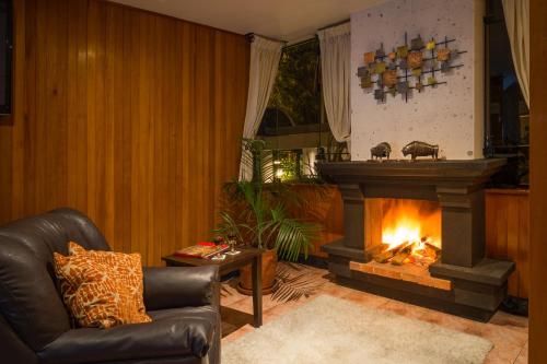 a living room with a fireplace and a leather chair at Natura Inn Hotel in Arequipa