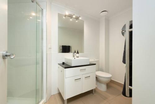 a white bathroom with a sink and a shower at Awesome Downtown Location - park the car and walk to everything ! in Mount Maunganui